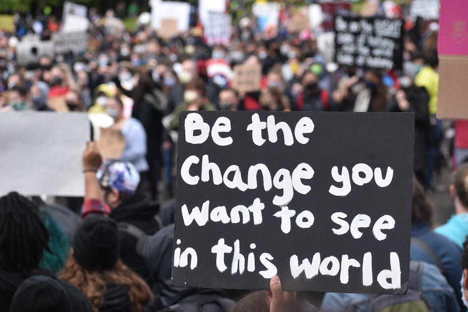 Protest crowd holding motivational sign at outdoor human rights rally.